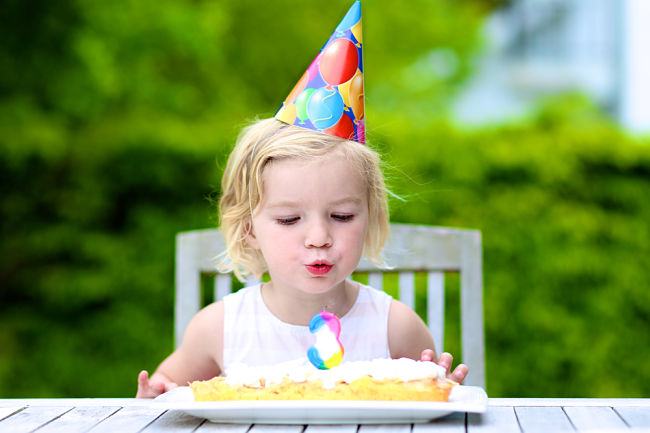 Bambina che festeggia il compleanno spegnendo le candeline