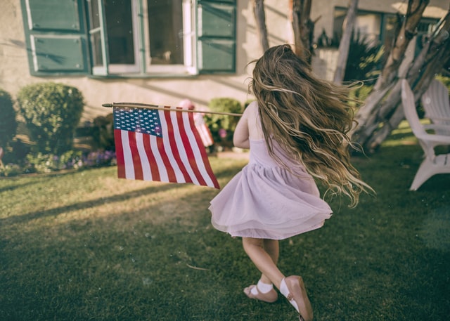 bambina che corre con la bandiera americana giocando al gioco ruba bandiera