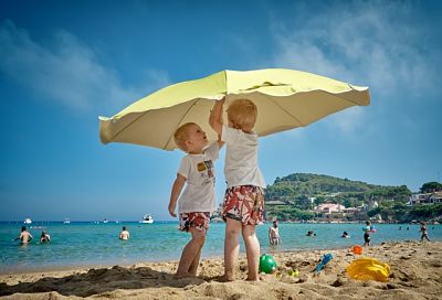 Bambini sotto l'ombrellone che giocano sulla spiaggia
