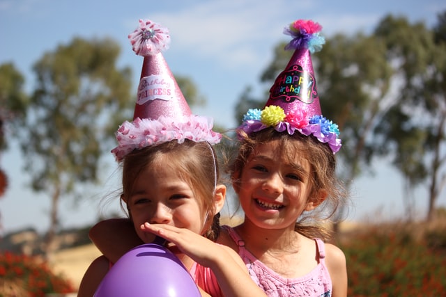 Bambine che festeggiano un compleanno con cappelli da festa e palloncini