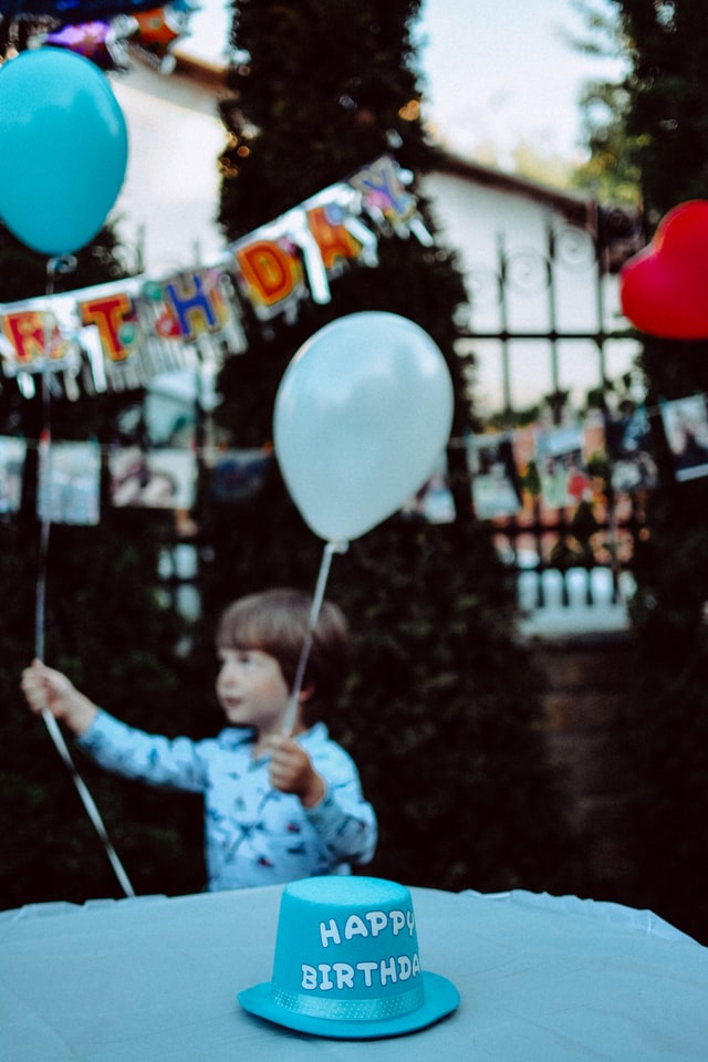 Bambino a una festa di compleanno che tiene in mano i palloncini