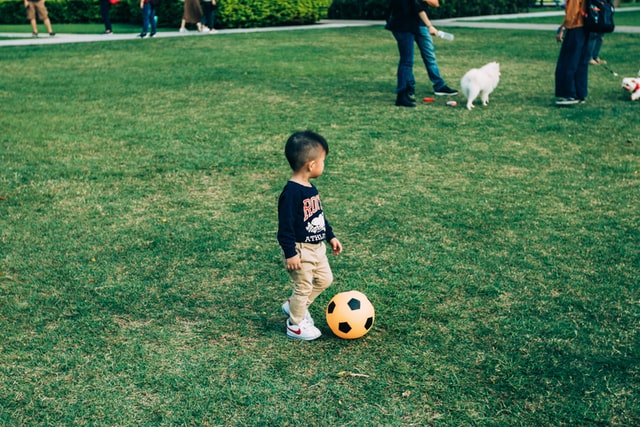 Bambino gioca a calcio su un prato d'erba