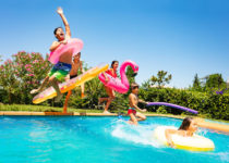 Amici felici che saltano in piscina durante un pool party