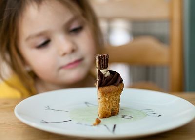 Bambina che guarda una fetta di torta ad un compleanno