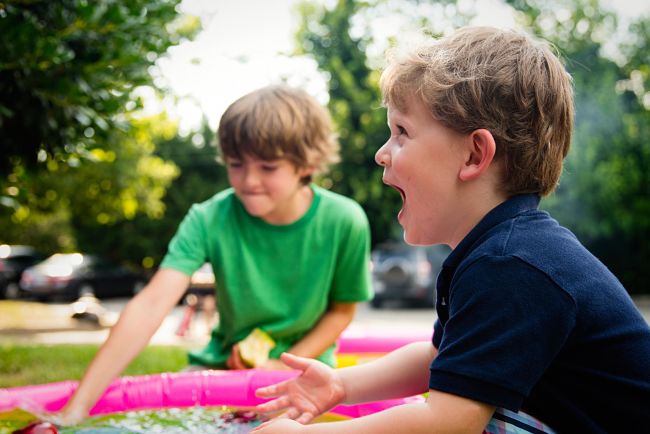 Due bambini, uno gioca e l'altro bambino urla perchè il laboratorio è terminato.