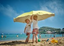Bambini sotto l'ombrellone che giocano sulla spiaggia