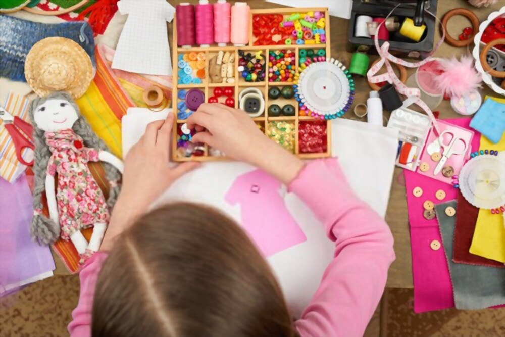 Bambina che sceglie come decorare il vestito appena realizzato per la sua bambola durante una festa dal sarto