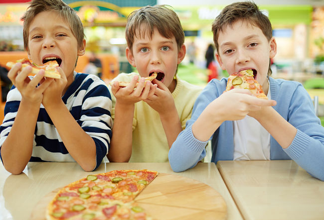 bambini grandi mangiano la pizza in pizzeria