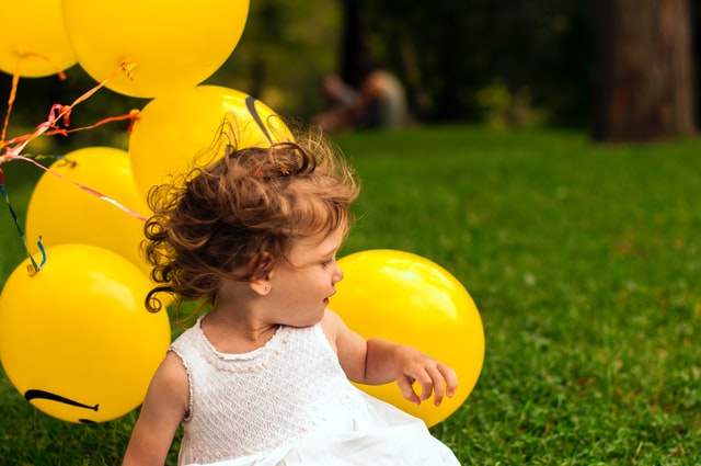Bambina piccola al parco circondata da palloncini gialli!