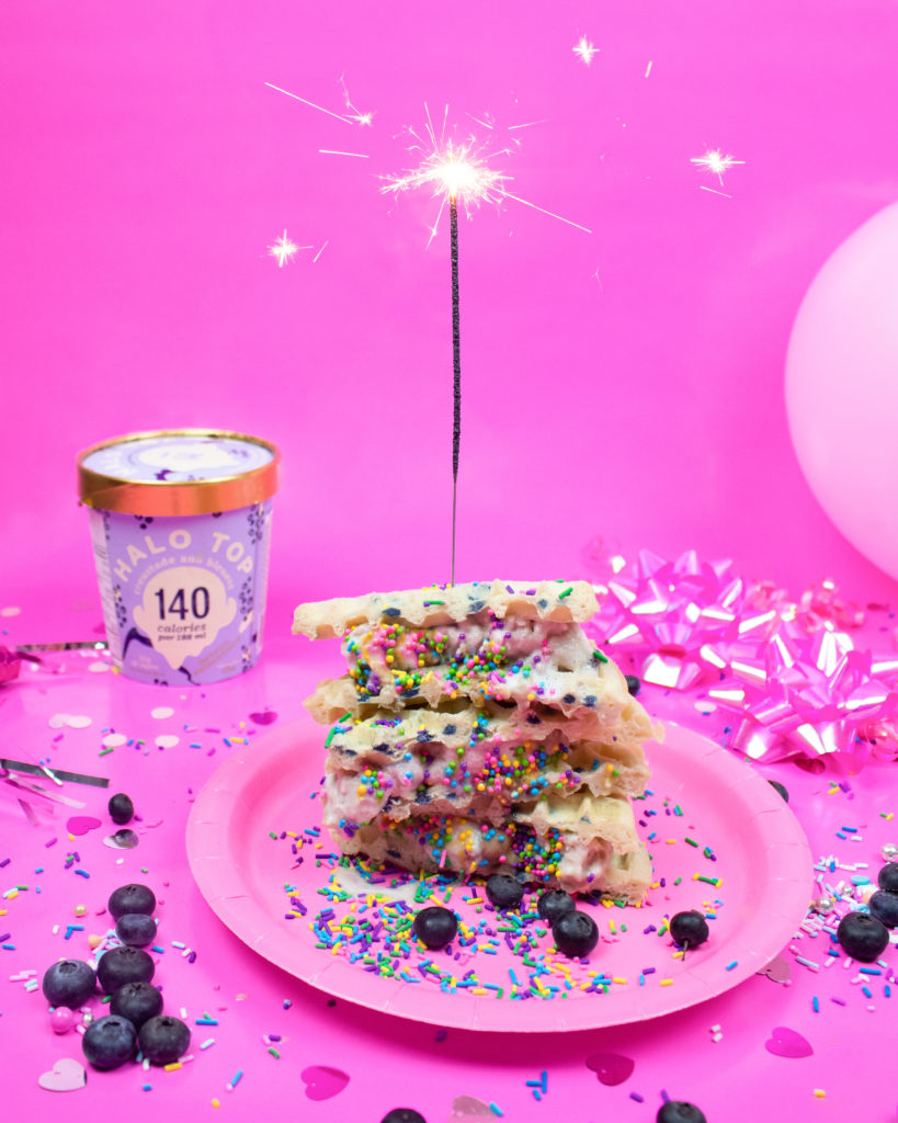 dolce su un piatto rosa decorato con more, glassa e zuccherini su uno sfondo rosa buffet per una festa di complanno per bambini.