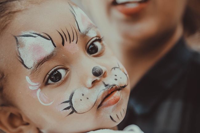 Bambina dopo il laboratorio di truccabimbi ad una festa per bambini, dipinta con il viso da gatto