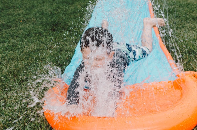 bambino che scivola con un gonfiabile ad acqua, affittato tramite un servizio di noleggio gonfiabili