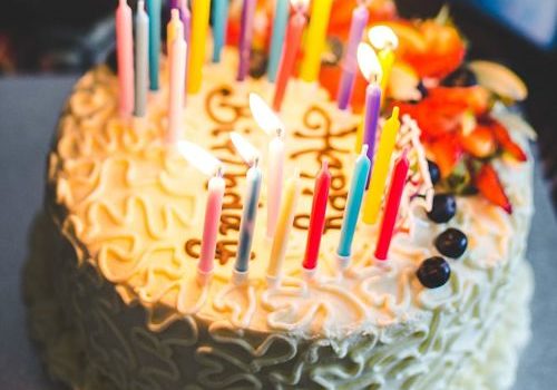 torta di compleanno con candeline accese e scritta happy birthday