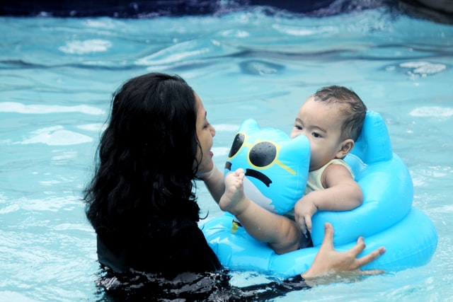 bambino che nuota con una ciambella controllato dalla mamma