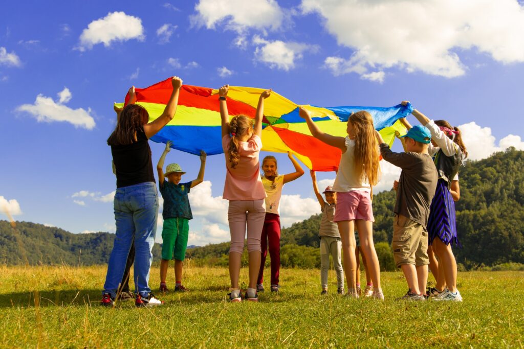 Giochi per bambini: gruppo di bambini che gioca all'aperto con telo